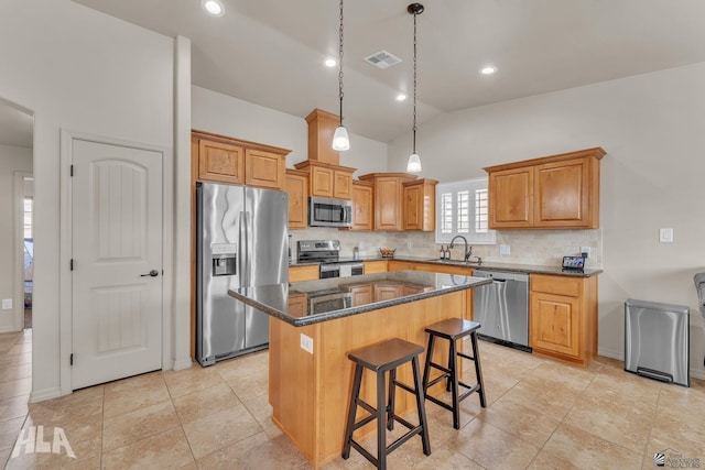 kitchen featuring visible vents, a kitchen island, a kitchen bar, appliances with stainless steel finishes, and a sink