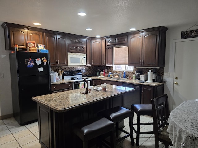 kitchen with dark brown cabinetry, black fridge, a center island, and stainless steel range with electric stovetop