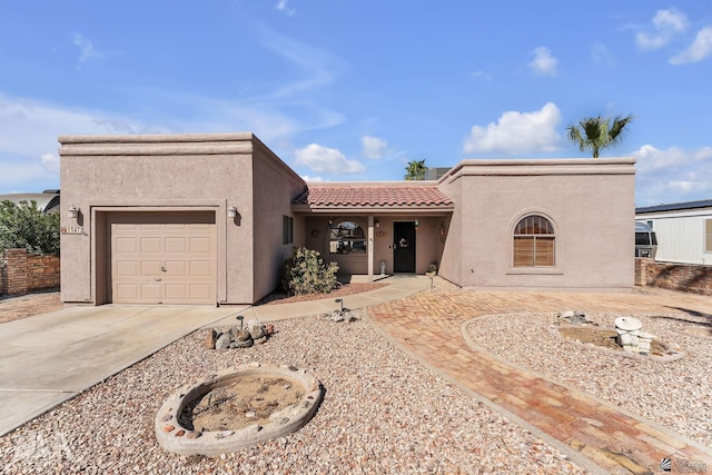 view of front of house with concrete driveway, a tile roof, an attached garage, and stucco siding