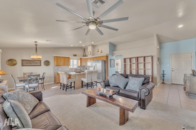 tiled living room with lofted ceiling, a textured ceiling, and ceiling fan