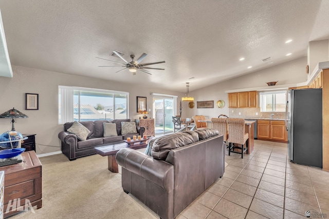 living room with lofted ceiling, ceiling fan, light tile patterned floors, and a textured ceiling