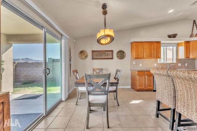 dining area with a mountain view, vaulted ceiling, and light tile patterned flooring