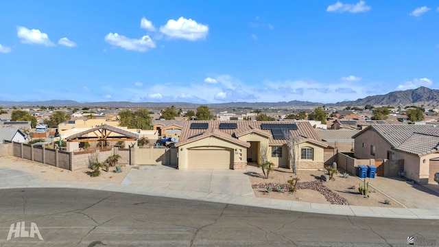 view of front facade featuring a garage, a mountain view, and solar panels