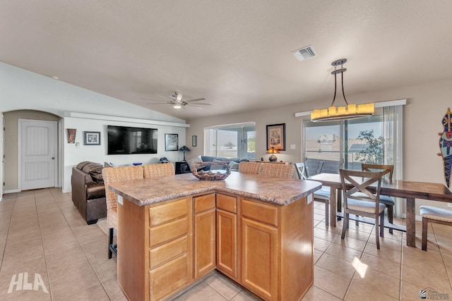 kitchen featuring pendant lighting, lofted ceiling, a center island, and light tile patterned flooring