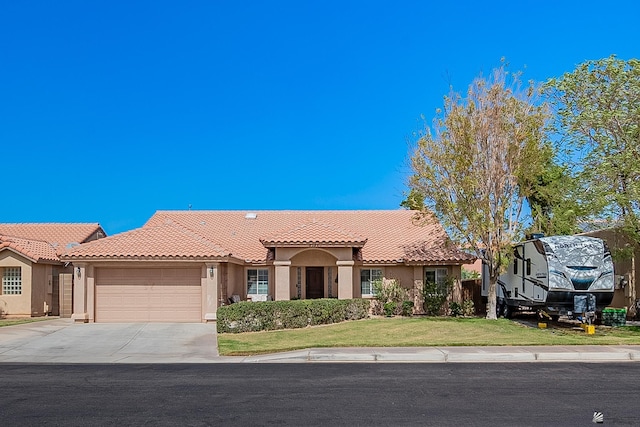 mediterranean / spanish-style house with driveway, a garage, a tiled roof, a front lawn, and stucco siding