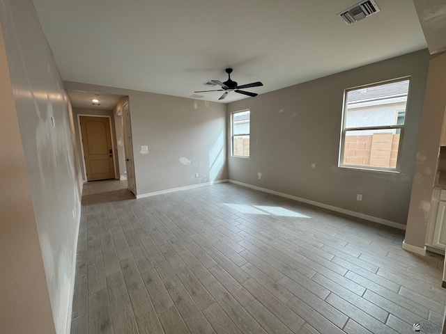 empty room with a ceiling fan, baseboards, visible vents, and wood finished floors