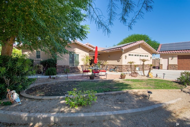 view of front of home with solar panels, a patio area, and a garage