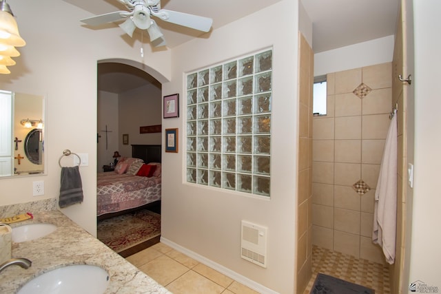 bathroom featuring a tile shower, ceiling fan, tile patterned flooring, heating unit, and vanity