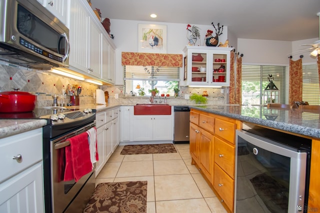 kitchen featuring stone counters, white cabinets, wine cooler, tasteful backsplash, and stainless steel appliances