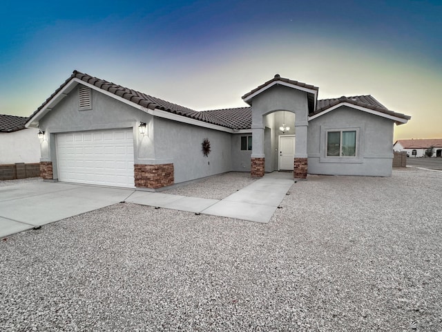 view of front of property featuring an attached garage, driveway, a tiled roof, and stucco siding