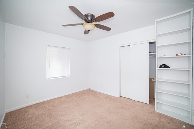 unfurnished bedroom with ceiling fan, light carpet, and a closet