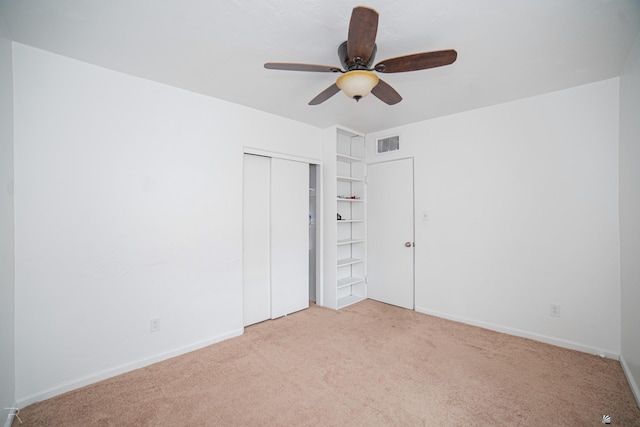 unfurnished bedroom with ceiling fan, light carpet, and a closet