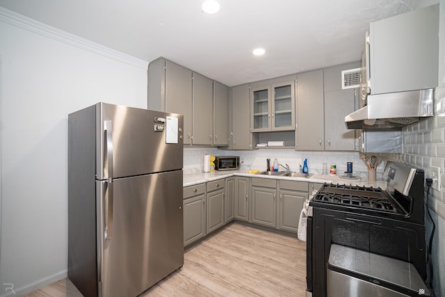 kitchen featuring appliances with stainless steel finishes, tasteful backsplash, gray cabinetry, sink, and light hardwood / wood-style flooring