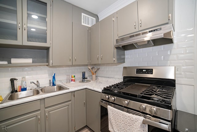 kitchen with gray cabinetry, stainless steel gas stove, decorative backsplash, and sink