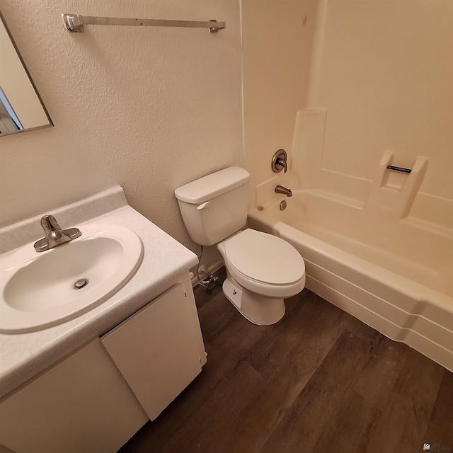 full bathroom featuring hardwood / wood-style flooring, vanity, washtub / shower combination, and toilet