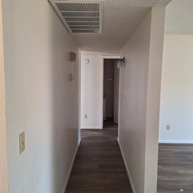 hallway featuring dark hardwood / wood-style floors and a textured ceiling