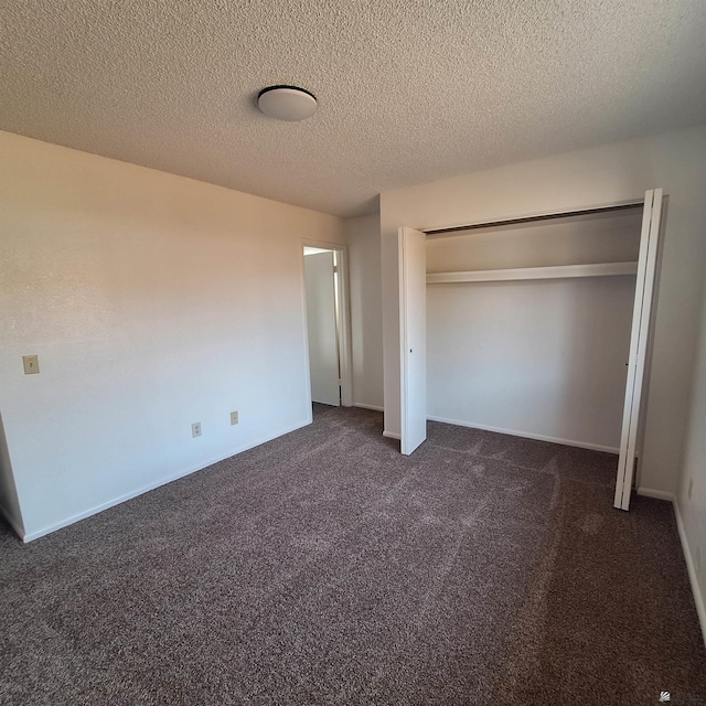 unfurnished bedroom with dark carpet, a closet, and a textured ceiling