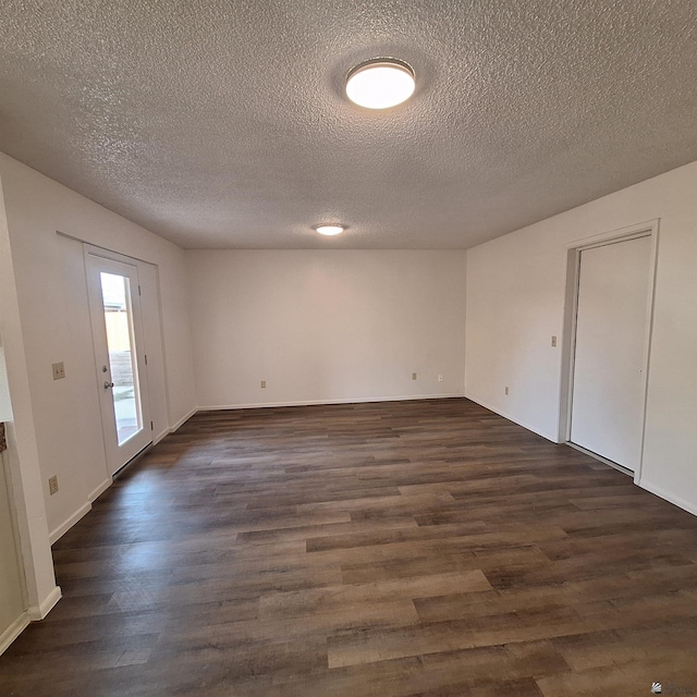 unfurnished room with dark hardwood / wood-style flooring and a textured ceiling