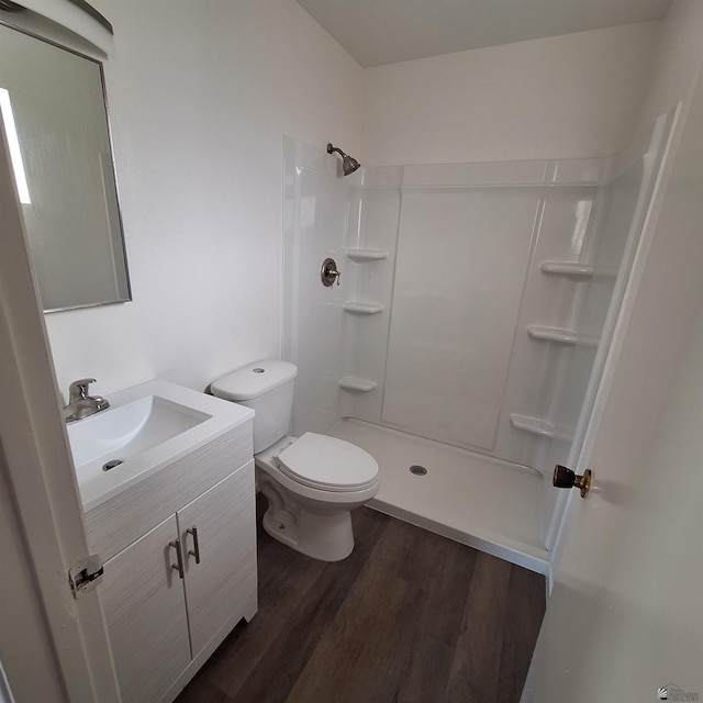 bathroom with hardwood / wood-style flooring, a shower, vanity, and toilet