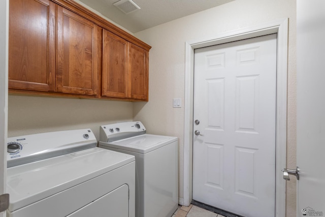 washroom with cabinets, separate washer and dryer, and light tile patterned floors