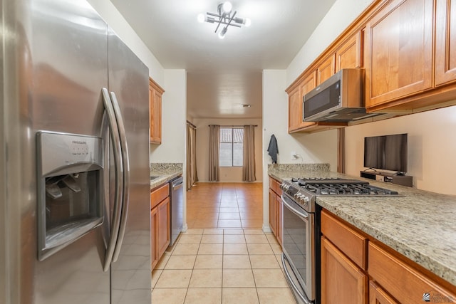 kitchen with stainless steel appliances, light tile patterned flooring, and light stone countertops