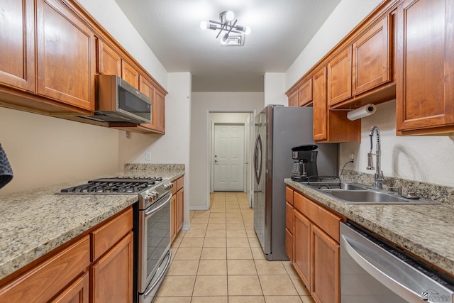 kitchen featuring light tile patterned flooring, appliances with stainless steel finishes, light stone countertops, and sink