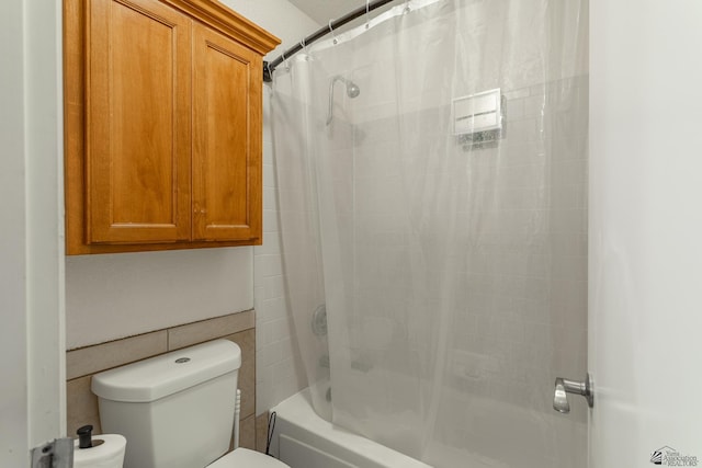 bathroom featuring toilet, shower / bath combo with shower curtain, and tile walls