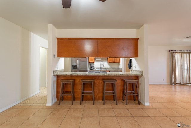 kitchen featuring light tile patterned flooring, stainless steel appliances, a kitchen breakfast bar, and kitchen peninsula