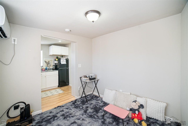 interior space with an AC wall unit, black refrigerator, and light hardwood / wood-style flooring