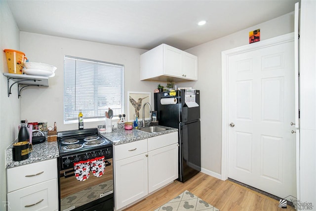 kitchen with light stone countertops, white cabinetry, sink, black appliances, and light wood-type flooring