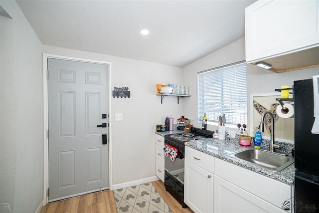 kitchen featuring black range with electric cooktop, white cabinetry, sink, and light wood-type flooring