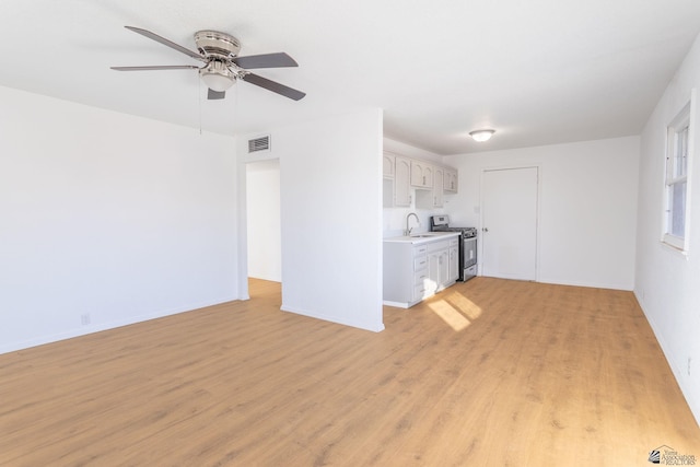 unfurnished living room with sink, ceiling fan, and light hardwood / wood-style floors