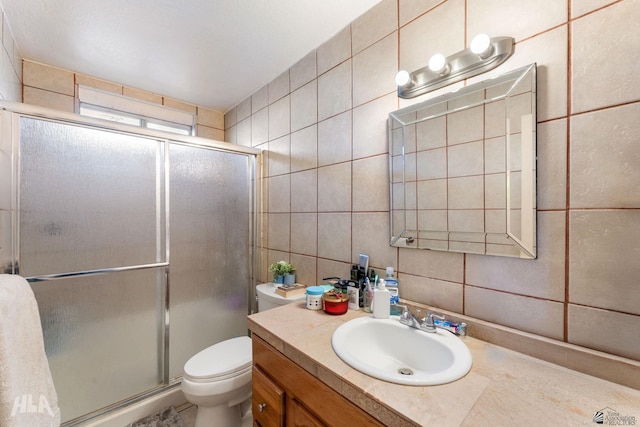 bathroom with toilet, an enclosed shower, vanity, and tile walls