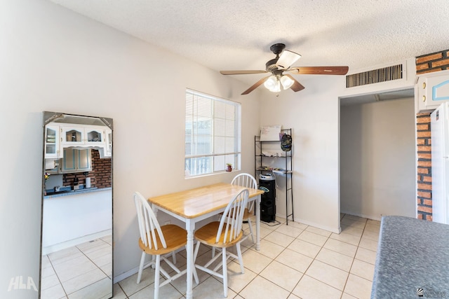 tiled dining space featuring a textured ceiling and ceiling fan