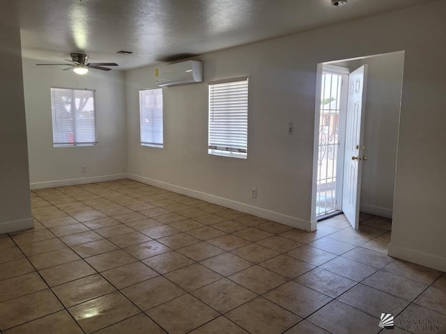 tiled spare room featuring an AC wall unit and ceiling fan