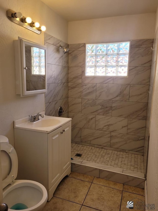 bathroom featuring tile patterned floors, vanity, toilet, and a tile shower