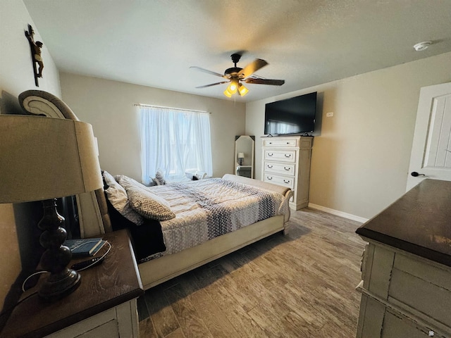 bedroom featuring wood finished floors, baseboards, and ceiling fan