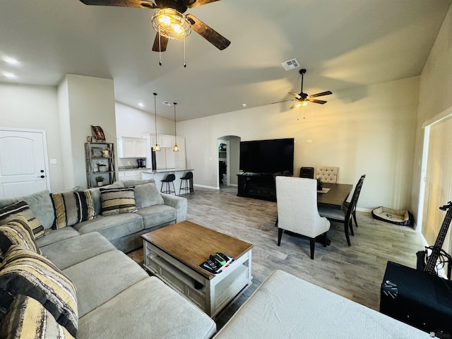 living area with light wood-type flooring, visible vents, high vaulted ceiling, a ceiling fan, and arched walkways