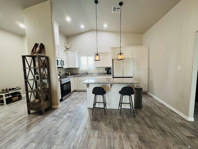 kitchen with wood finished floors, visible vents, a sink, appliances with stainless steel finishes, and a center island