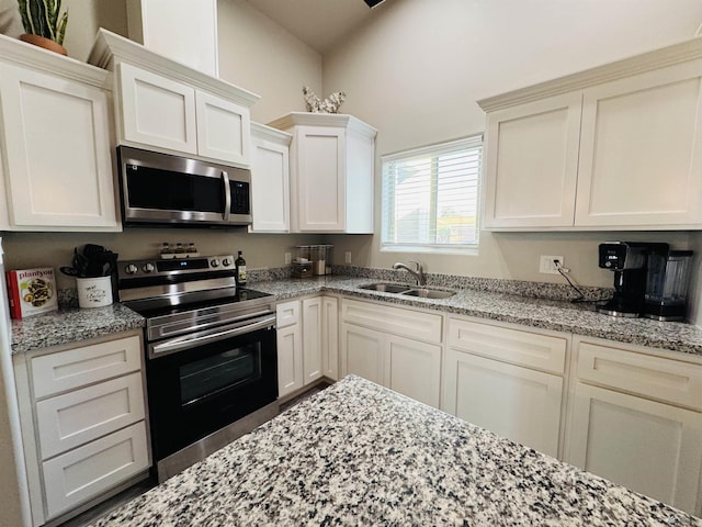 kitchen featuring a sink, light stone countertops, appliances with stainless steel finishes, and white cabinets