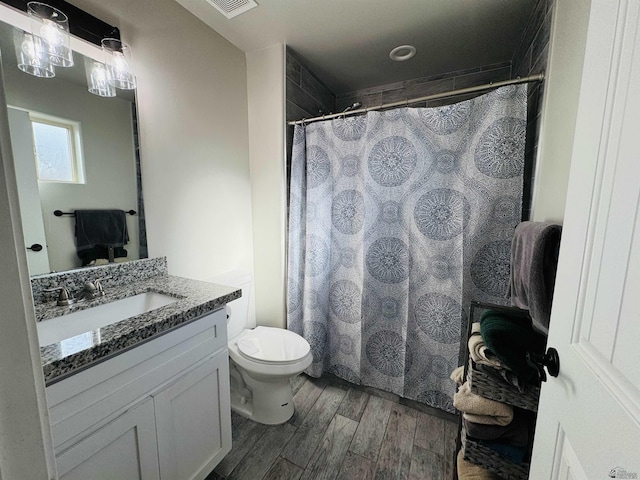 bathroom featuring visible vents, toilet, a shower with curtain, wood finished floors, and vanity