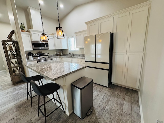 kitchen with light wood-style flooring, a sink, a kitchen breakfast bar, a kitchen island, and appliances with stainless steel finishes