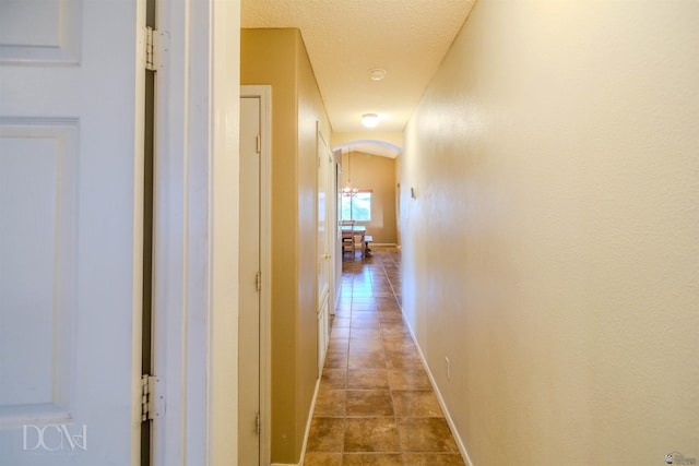 hallway with a textured ceiling and tile patterned floors