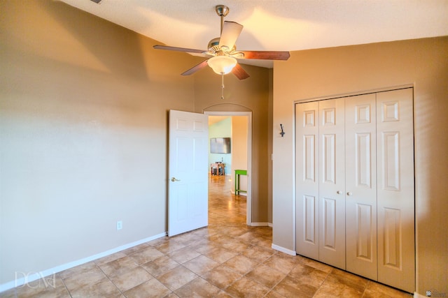 unfurnished bedroom featuring lofted ceiling, a closet, and ceiling fan