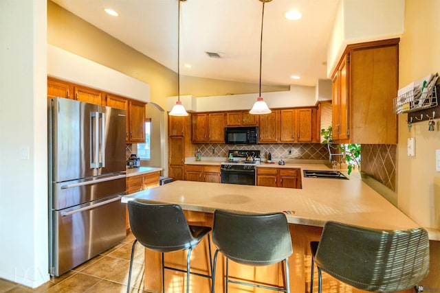 kitchen with vaulted ceiling, sink, range with gas cooktop, a breakfast bar, and high quality fridge