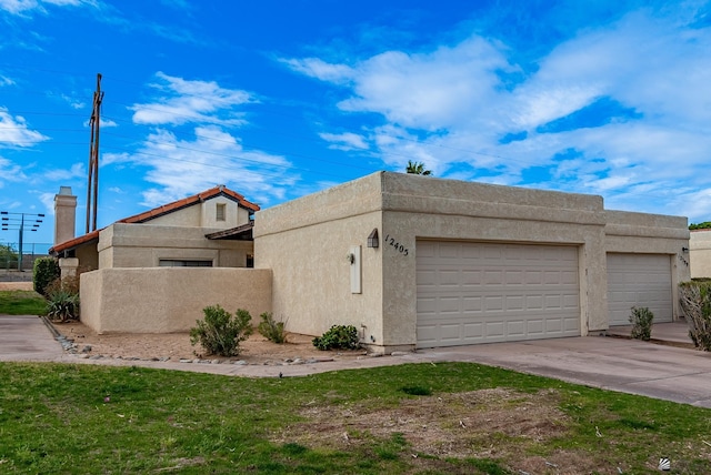 view of side of property with stucco siding, driveway, and an attached garage