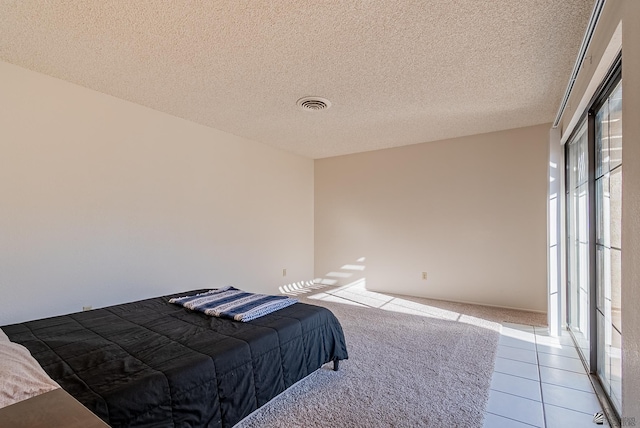 bedroom featuring light tile patterned floors, visible vents, and a textured ceiling