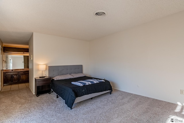 bedroom featuring visible vents, carpet floors, and a textured ceiling