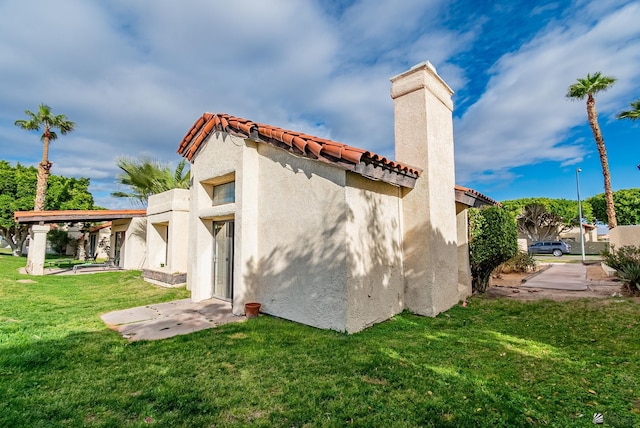 back of property featuring stucco siding, a lawn, and a tile roof