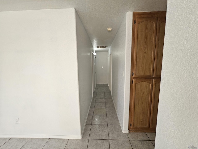 hall featuring light tile patterned flooring and a textured ceiling